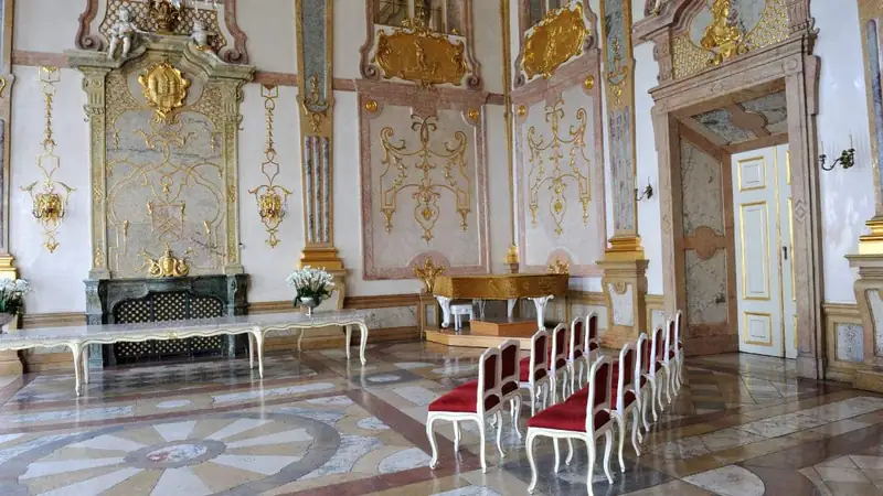 Columns, gilded decoration and red chairs in Mirabell’s Marble Hall