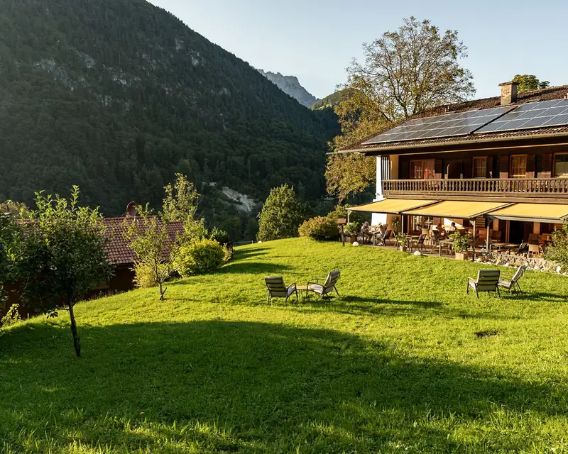 Garten und Terrasse des Lampllehen in der Abendsonne, dahinter die Berge